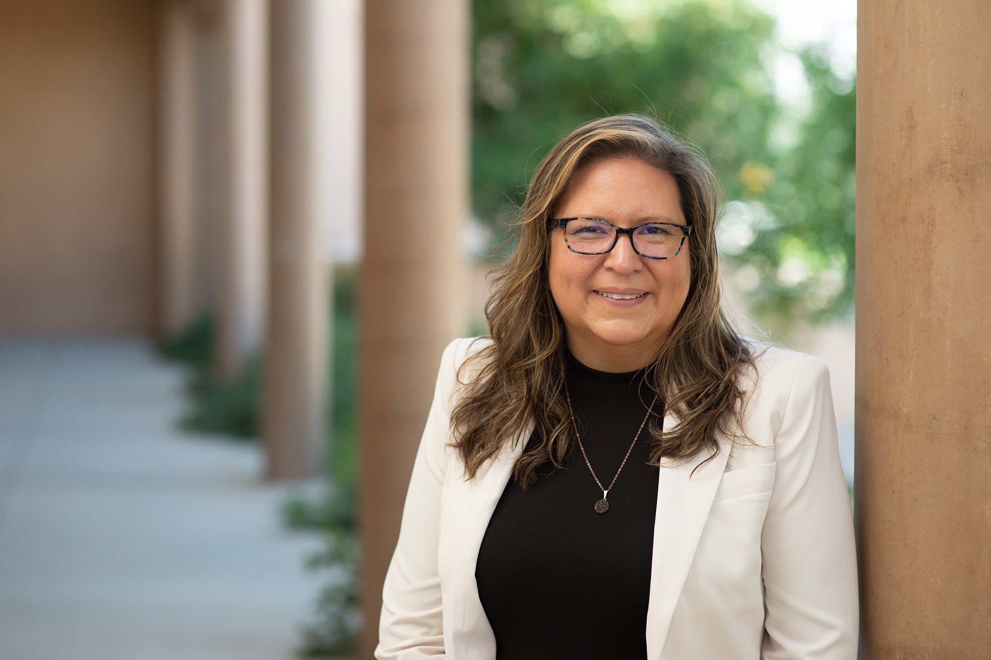 Lydia Tapia standing beside a column on the University of New Mexico campus